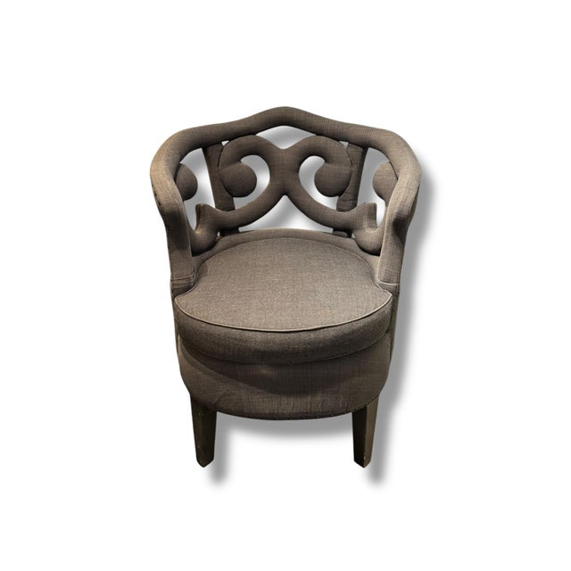 Striking pair of upholstered accent chairs featuring dramatic scrollwork backs, curved silhouettes, and decorative...