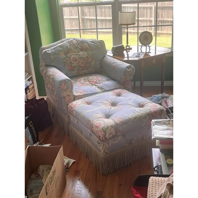 The armchair features a classic blue floral chintz upholstery with a prominent ribbon and bouquet motif, embodying a...