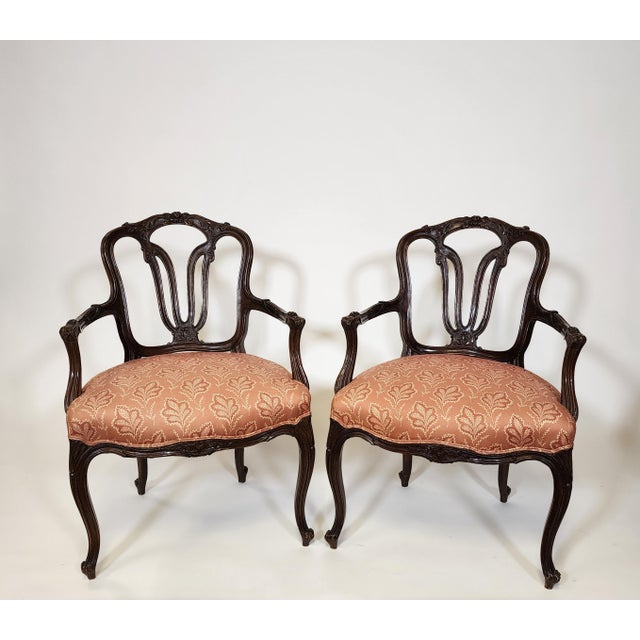 French inspired armchairs with carved floral details upholstered in terracotta cotton print. These armchairs are in...