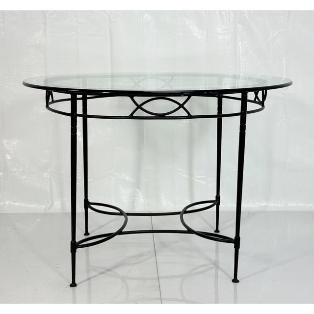An elegant round dining table designed by Mario Papperzini for Janus et Cie, featuring a sculptural black wrought iron...