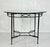 An elegant round dining table designed by Mario Papperzini for Janus et Cie, featuring a sculptural black wrought iron...