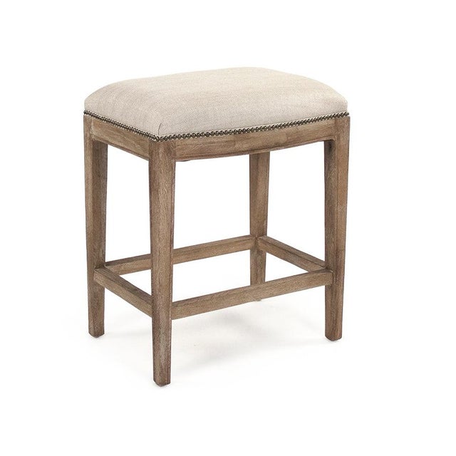 The Cora Counter Stool from Zentique is a clean-lined backless stool with a padded linen seat, brass nailhead trim, and...
