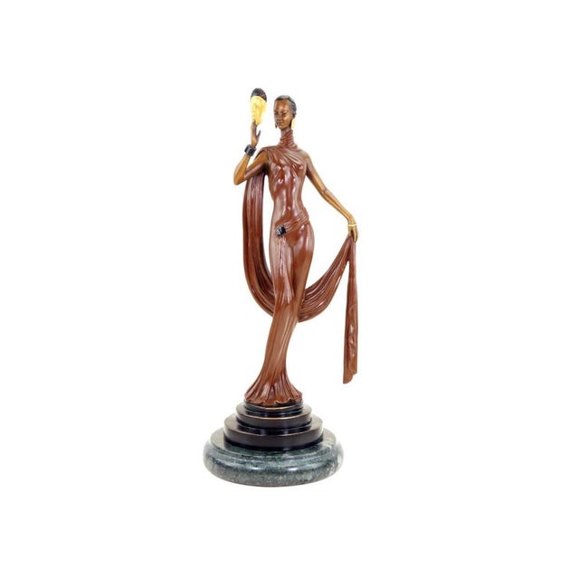 This solid bronze sculpture captures a dancer in an elegant pose, dressed in a long gown with fluid drapery. She lifts a...