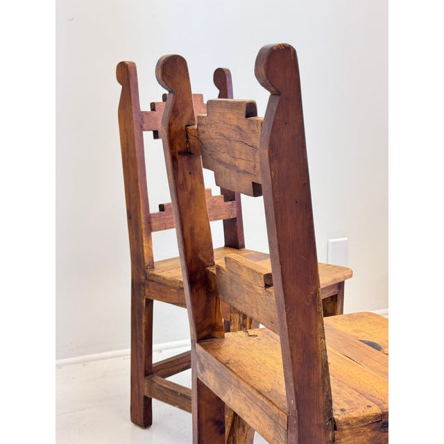 A striking pair of mid-century Mexican rustic wooden chairs, circa 1950–1970, distinguished by their unusual geometric...