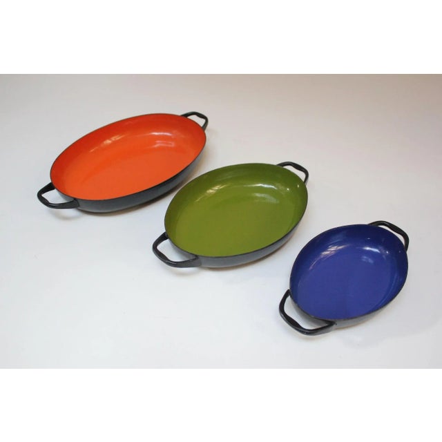 Set of three 1950s frying / sauté pans in blue, lime green and orange enameled metal with black handles. Given the varying...