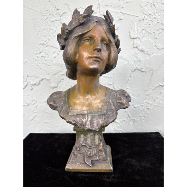 This finely modeled Art Nouveau bust titled “Enid” depicts a serene young woman crowned with a laurel wreath, a classical...