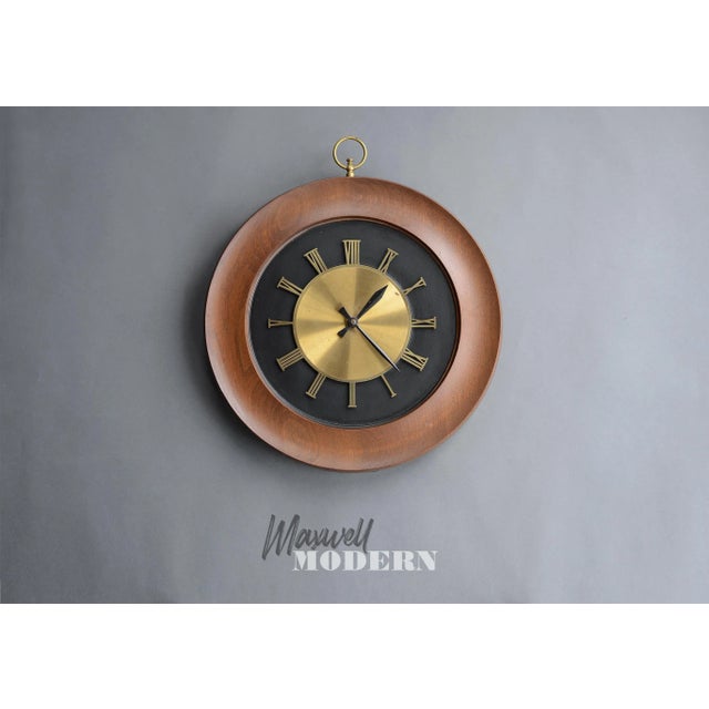 Gorgeous large mid century modern wall clock (16" diameter) with sculpted walnut wood and brass accents. Clock face has...