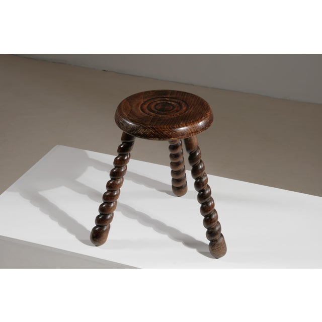 This 1950s French-made wooden tripod stool features a round seat and three twisted legs, giving it a unique and elegant...