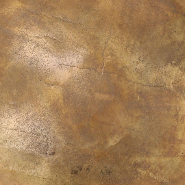 Modern round brass finish cast aluminum coffee table with a sculptural pedestal base and richly textured antiqued surface....