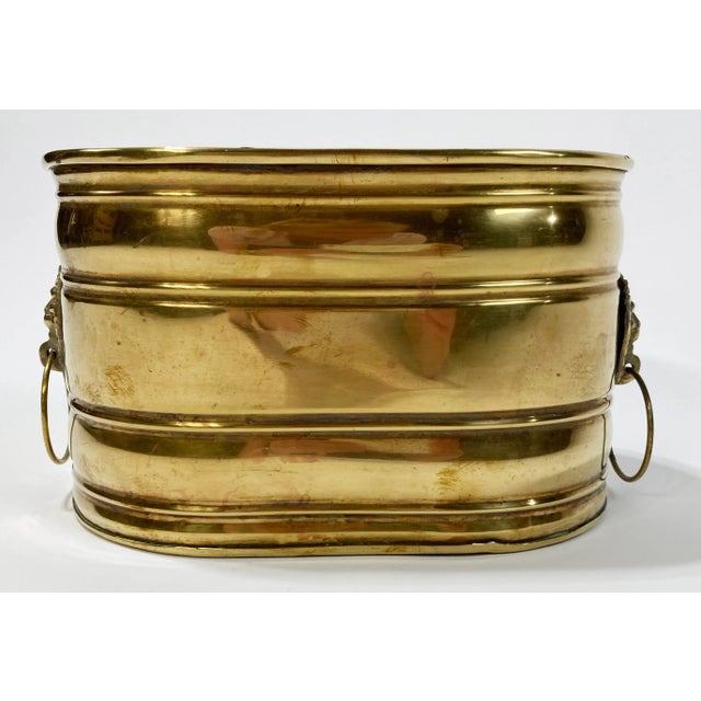 Vintage oblong decorative brass planter featuring lion head ringed handles at each end. Interior measures 10"W x 6.5"D....