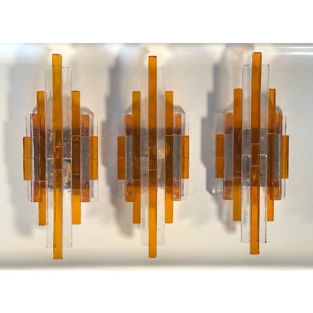 3 70s wall lamps by Poliarte, transparent and orange glass, metal structure, can be placed on the wall both horizontally...