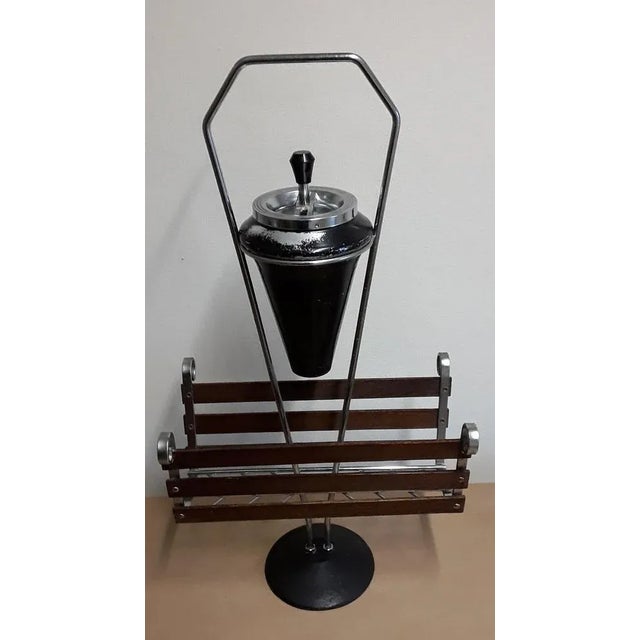 Vintage newspaper rack from the 60s with chromed metal frame and teak struts on black iron base with ashtray insert.