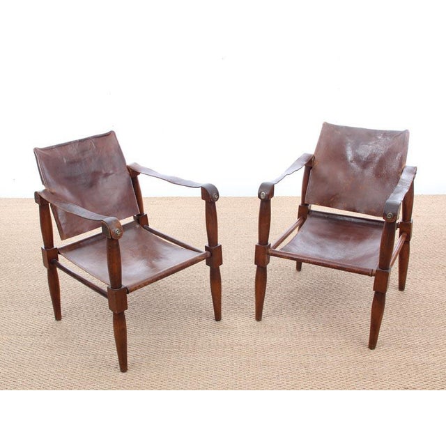 This pair of safari chairs in beech and brown patinated leather was manufactured in the 1940s.
