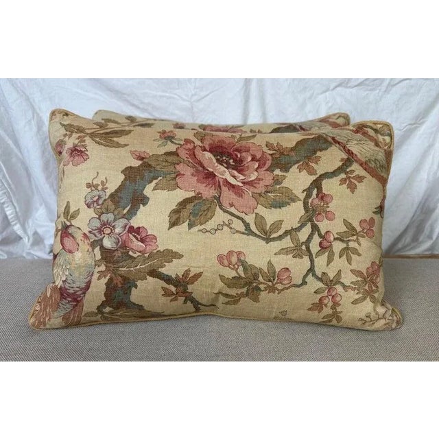 This pair of decorative lumbar pillows features an elegant vintage-style floral design on a warm beige background. The...