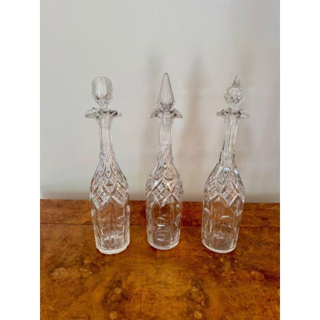 Unusual trio of antique Edwardian cut glass decanters, having an unusual trio of cut glass decanters having a tall slender...