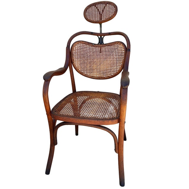 Late Victorian Austrian bent oak and brass barbers chair with a cane seat and backrest featuring an elegant, sculptural...