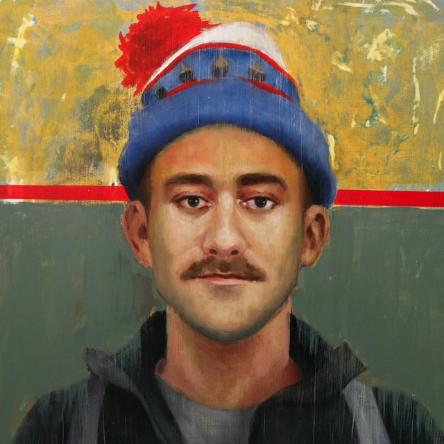 Benny by Fikriye Oz | Oil on panel Portrait of a man wearing a hat with a red pom-pom. For Sale