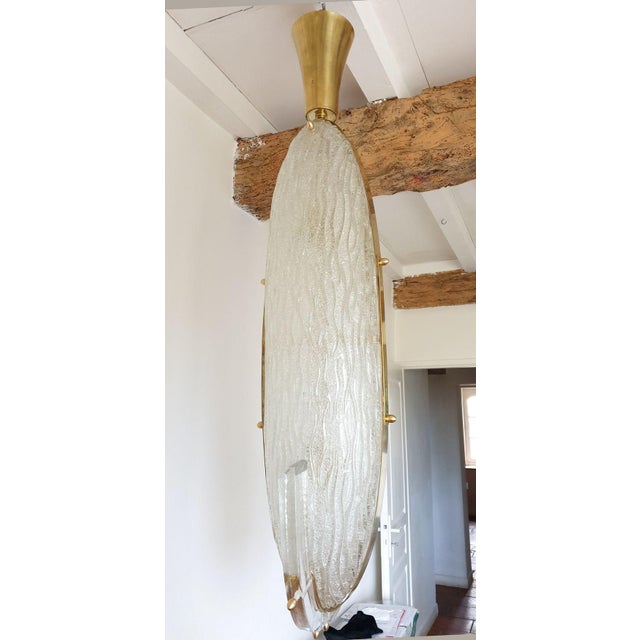 Mid-Century Modern pendant ceiling light, or large lantern, with a long oval shape, in clear Murano glass and brass...