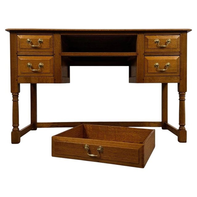 A handsome 20th-century English writing table accompanied by its matching stool, finely crafted from golden oak and...