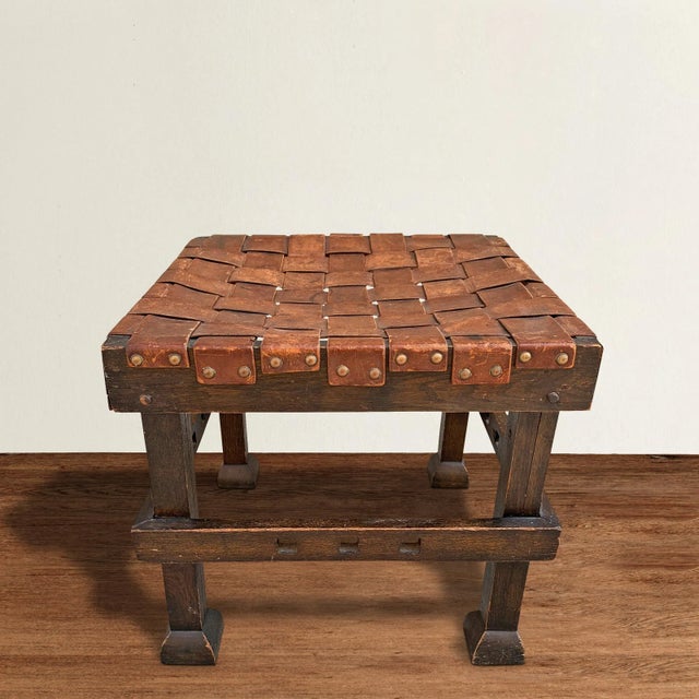 A wonderful early 20th Century English Arts & Crafts period oak stool with its original woven leather top with brass...