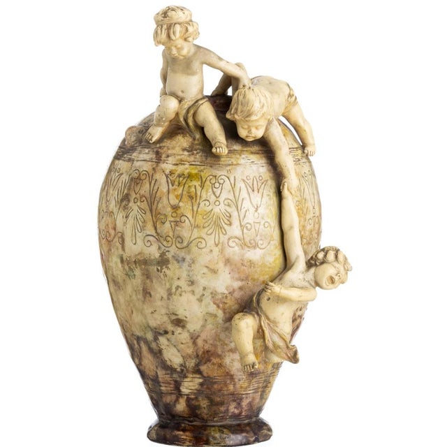 Large Pitcher German, circa 1893. Ceramic with embossed decoration depicting putti and vegetal motifs. Marked on the base....