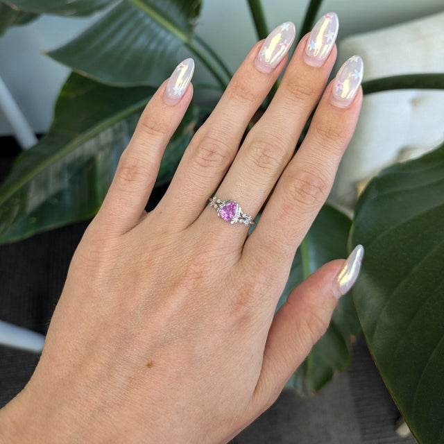 A natural pink sapphire glows softly within a halo of brilliant diamonds in this pear-shaped ring, crafted in solid 14K...