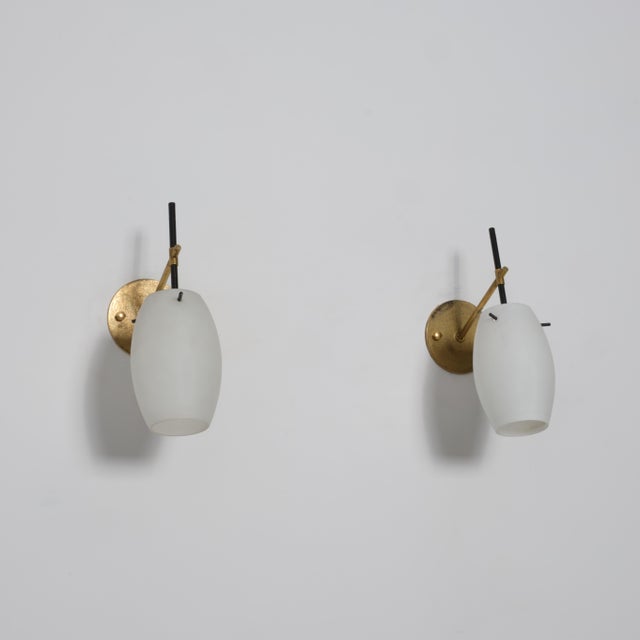 Pair of Italian wall sconces from the 1950s defined by a refined mid-century composition combining brass, black lacquered...