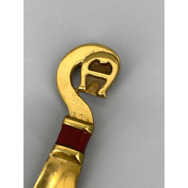 A set * by Etienne Aigner * Shoehorn/shoehorn/shoe pick and a brush * Shoehorn material: Brass * Color: Gold with patina *...