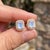 Adorn yourself with captivating iridescence with these delicate halo stud earrings, holding an emerald-cut natural rainbow...