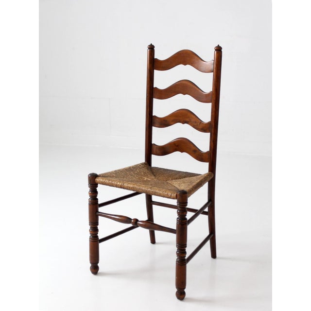 Vintage French Provincial ladderback chair featuring a warm walnut-toned finish, four gracefully shaped ladderback slats,...