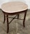Vintage accent side table featuring beautiful veined marble oval top in pinkish beige and rich wood toned faux bamboo...