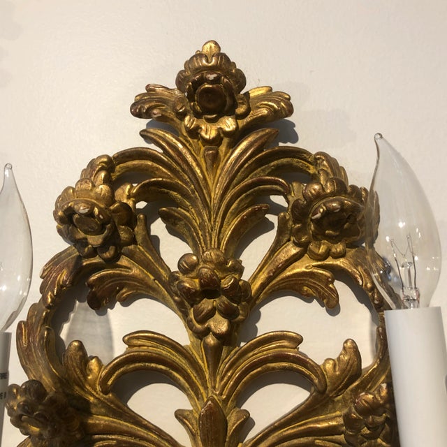 Pair of Hand carved wood sconce featuring a floral design with ribbon in a Vintaged gold gilt finish. Italy.