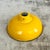 Mustard yellow enamelled coolie shade with glossy exterior, black rim, and white inner reflector. The wide dome form...