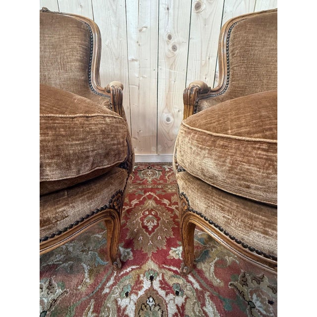 Pair of Louis XV style bergère armchairs upholstered in a rich brown velvet. Solid wood frame featuring the...