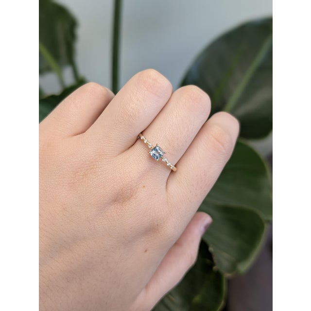 This minimalist 14K yellow gold ring features a dreamy round aquamarine from Brazil, flanked by tiny natural diamonds....