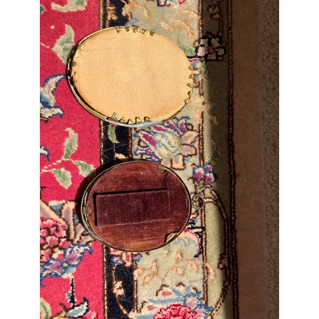 Two miniature portraits. Comprising two oval metal frames with glass fronts showing two youthful ladies in period...