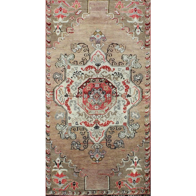 This vintage Turkish Oushak carpet (circa 1940) features a central blossoming medallion flower surrounded with smaller,...