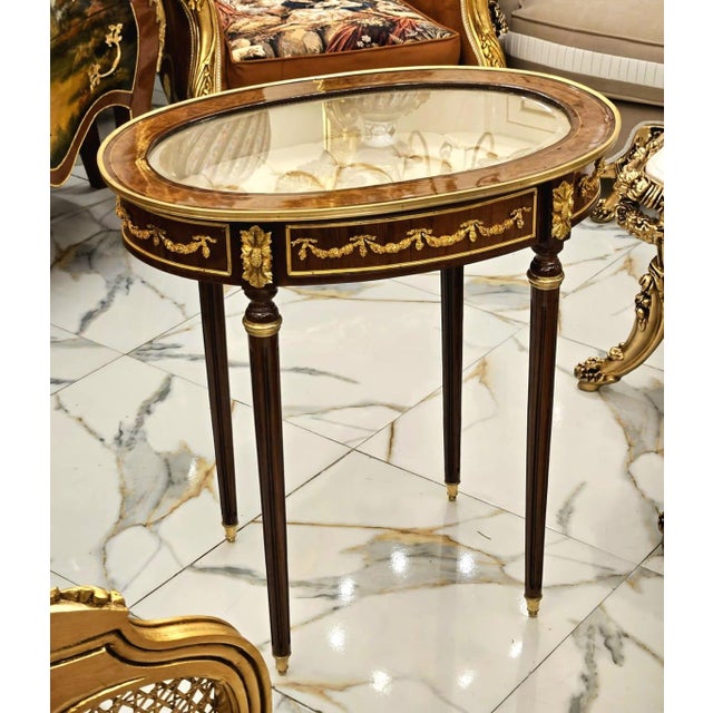 Showcase your treasured collectibles in timeless French elegance with this exquisite Louis XVI oval display side table....