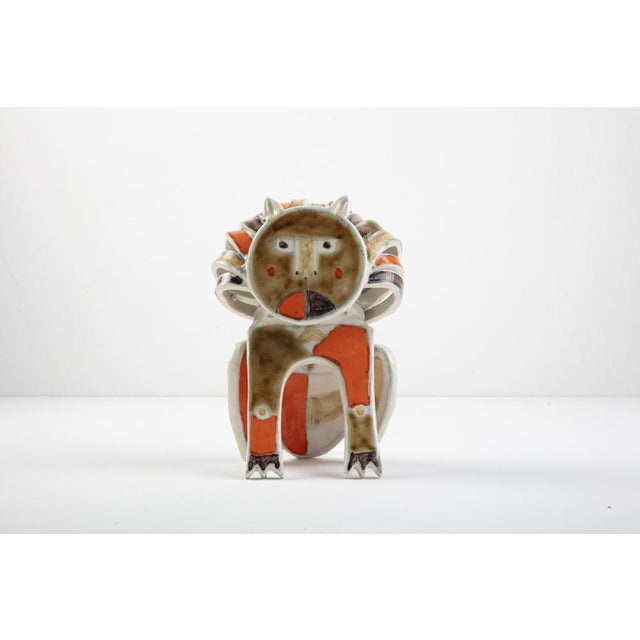 Sculpture depicting a seated lion, in glazed stoneware of various colors and signed “gambone italy” under the base....