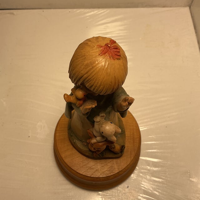 Hand carved figurine, featuring a girl with sweet face animals, one rabbit standing on another reaching up to be held by...