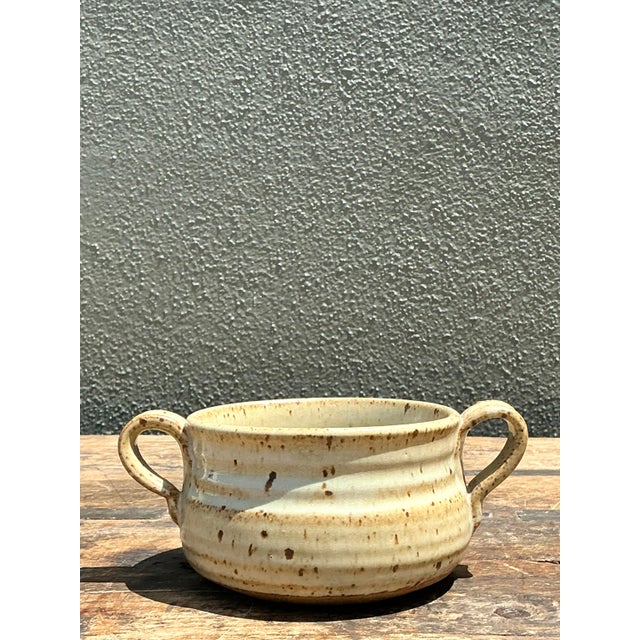 This vintage studio pottery bowl is a charming example of the 1970s organic craft movement, blending rustic warmth with...