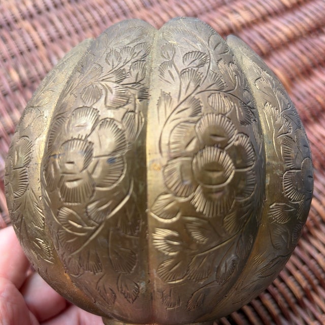 Vintage engraved brass bowl in a sculptural lotus form, resting on a raised pedestal base. The exterior features hand-...