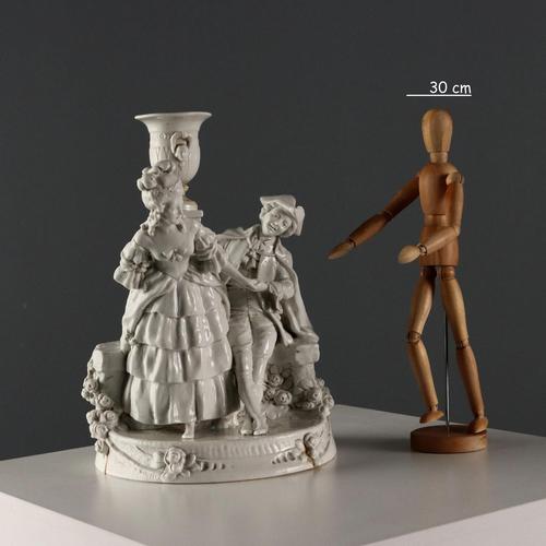 White porcelain sculpture depicting a romantic couple in a garden. The 18th-century clothing, hairstyles, faces, and the...