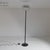 Floor lamp with a black marble base, painted metal stem, and curved glass shade with a striped decoration supported by a...