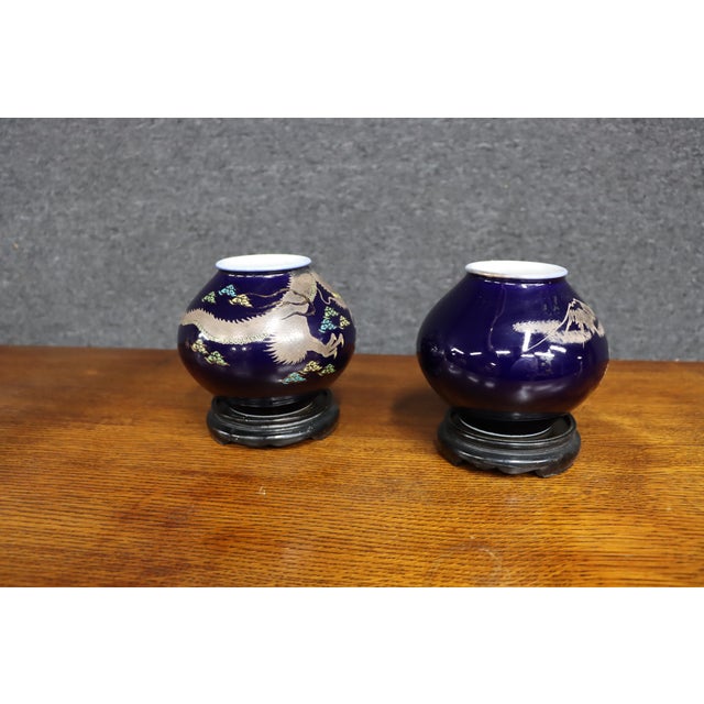 Pair of Japanese porcelain vases featuring deep cobalt blue grounds with applied copper-overlay decoration depicting...