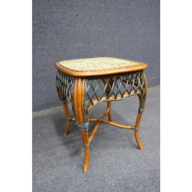 Wicker side table featuring a woven natural-fiber top, open lattice sides, and a curved bamboo-style frame in a warm honey...