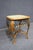 Wicker side table featuring a woven natural-fiber top, open lattice sides, and a curved bamboo-style frame in a warm honey...