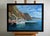 The painting "Ships on the Ferry" captures the essence of a peaceful coastal scene, where the shimmering blue waters of...