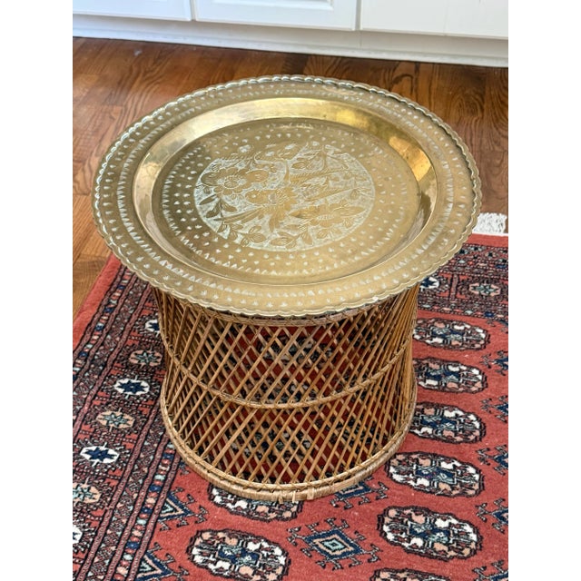 Vintage boho side table features an etched brass tray top that rests on a woven rattan base. Beautiful vintage patina. It...