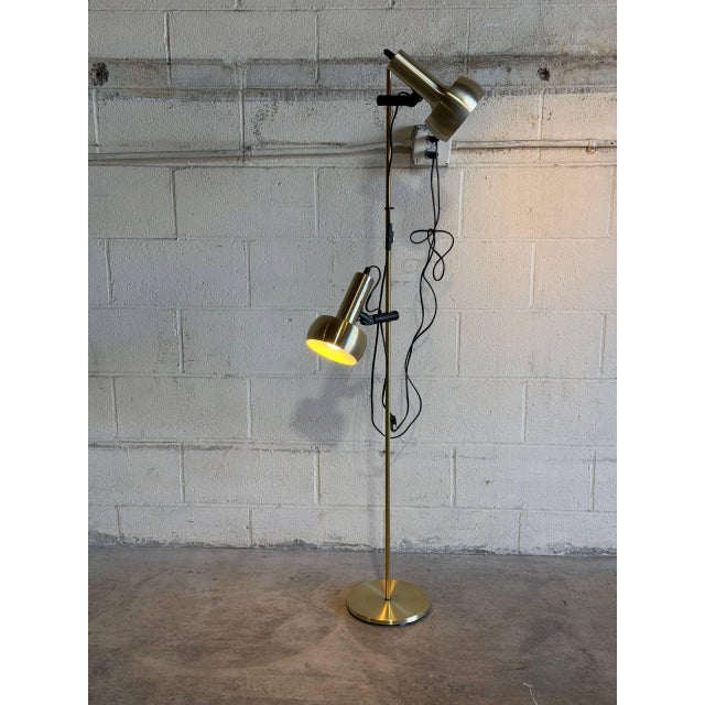 This striking gold standing lamp features dual adjustable cylindrical shades and a sleek metallic finish. The sculptural...